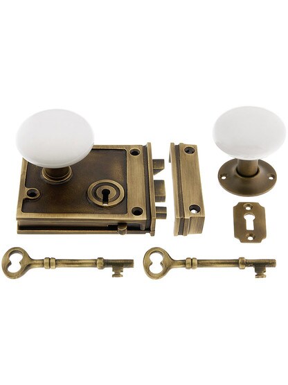 Solid Brass Horizontal Rim Lock Set with White Porcelain Knobs in Antique Brass.